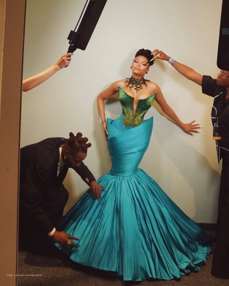 Bonang Matheba poses in a dramatic teal and green corseted gown by Veekee James, styled by Dahmola, against a neutral backdrop.