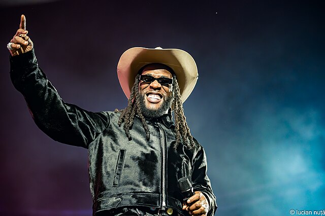 Nigerian artist Burna Boy on stage at Untold Festival, August 2024, pointing to the crowd during a global performance.
