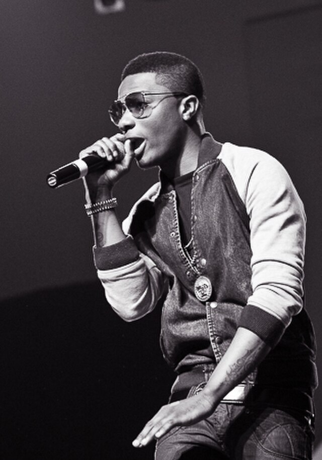 Wizkid singing on stage at a 2013 album launch concert, illuminated by stage lights, captured by TCD PHOTOGRAPHY.