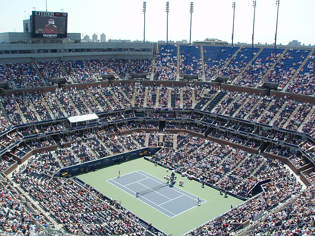 Wide shot of Arthur Ashe Stadium during the U.S. Open, showing a packed crowd under the roof.