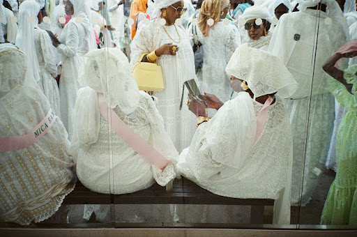 Women in white attire gathering together.