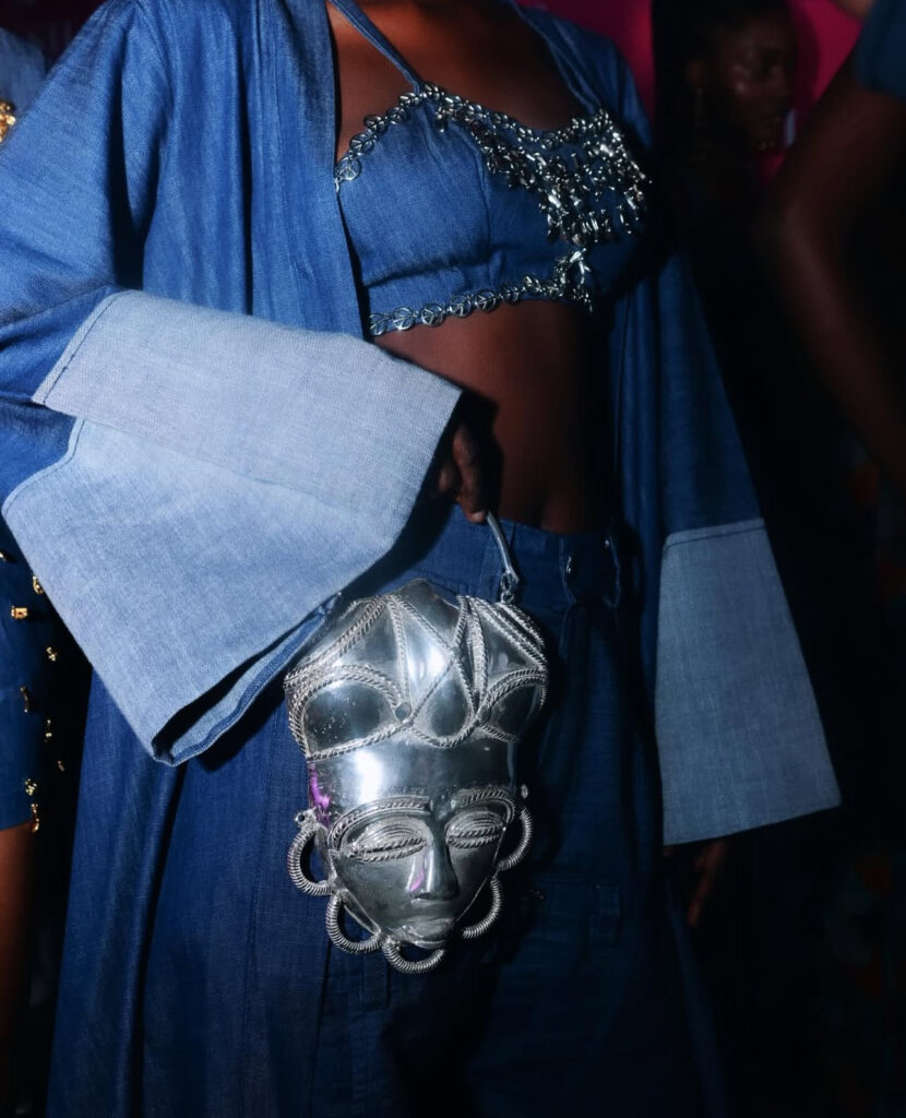 African Ritual Aesthetics in the Age of Luxury Fashion 4 Model in pale blue denim layers carrying a large silver shell-shaped bag, Adama Paris's Waridje collection