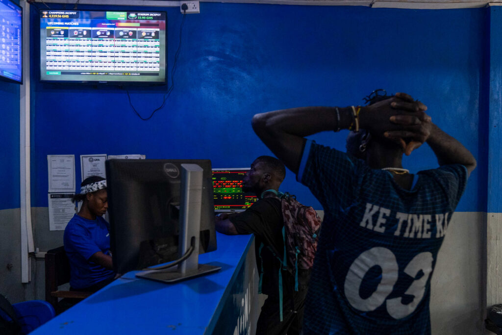 A man holds his head in front of a betting terminal displaying odds
