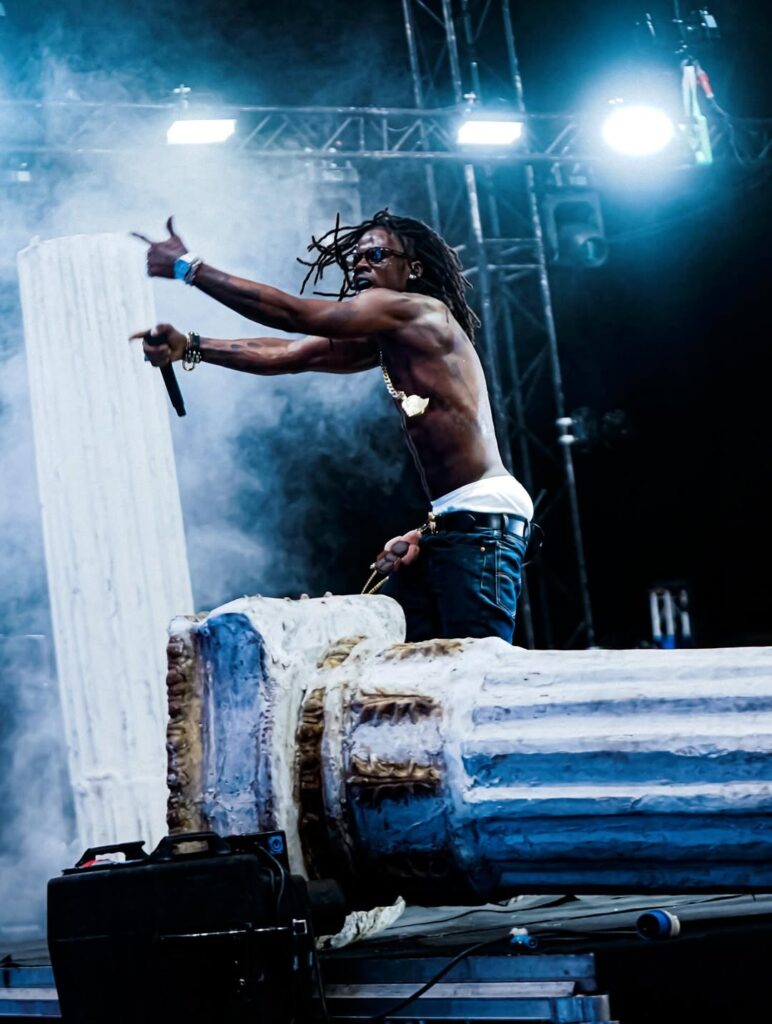 A performer on stage under bright lights with the crowd below
