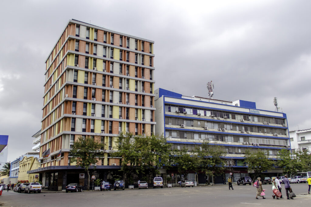 Color-blocked residential tower with coral, yellow, and navy facade panels. Prédio Spence e Lemos by Pancho Guedes, 1964, Maputo, Mozambique.