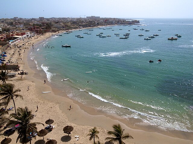 The Best Places to Propose in Africa: From Cape Town to Marrakech 7 Aerial view of Ngor Island in Dakar, Senegal, showing a cluster of red-roofed buildings surrounded by the turquoise waters of the Atlantic Ocean and a sandy shoreline.