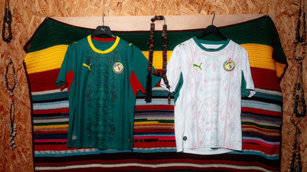The dark green home and white away PUMA Senegal 2026 World Cup jerseys hanging side-by-side on a rack.