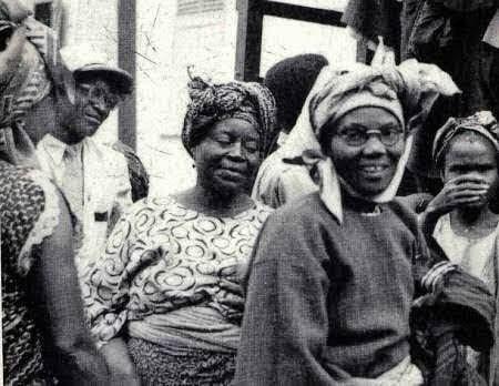 A historical black and white photograph of a group of women from the Abeokuta Women's Union, including Funmilayo Ransome-Kuti, standing together during their campaign for representation and tax reform in Nigeria.