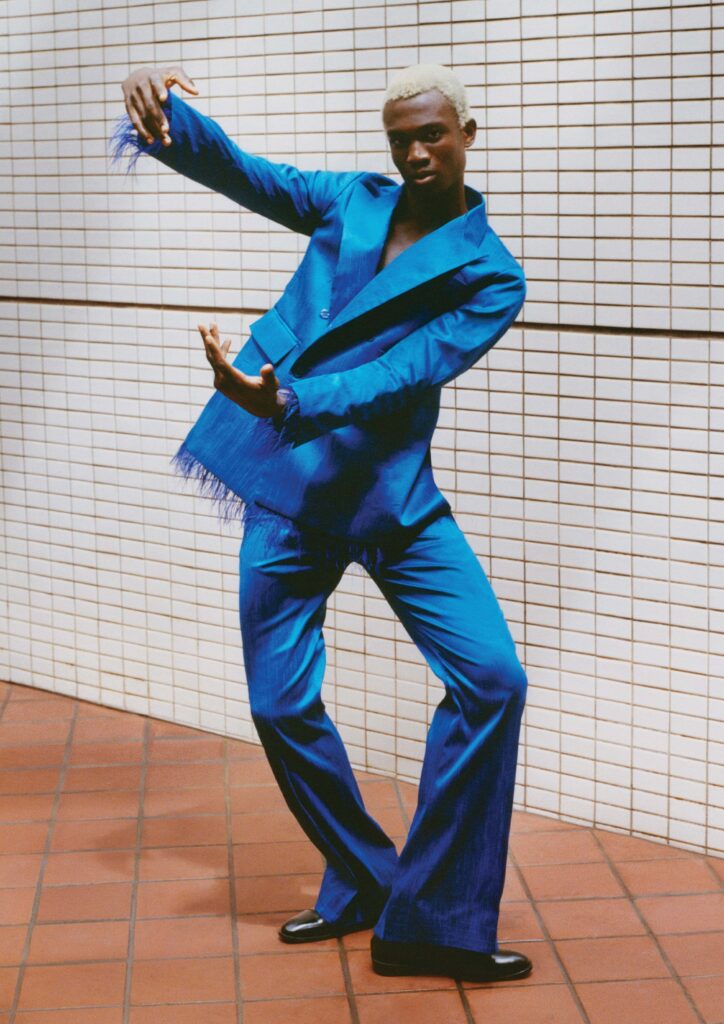 West African dancer in a blue designer suit posing in Accra for the Byredo Bal d’Afrique campaign, photography by Philip-Daniel Ducasse.