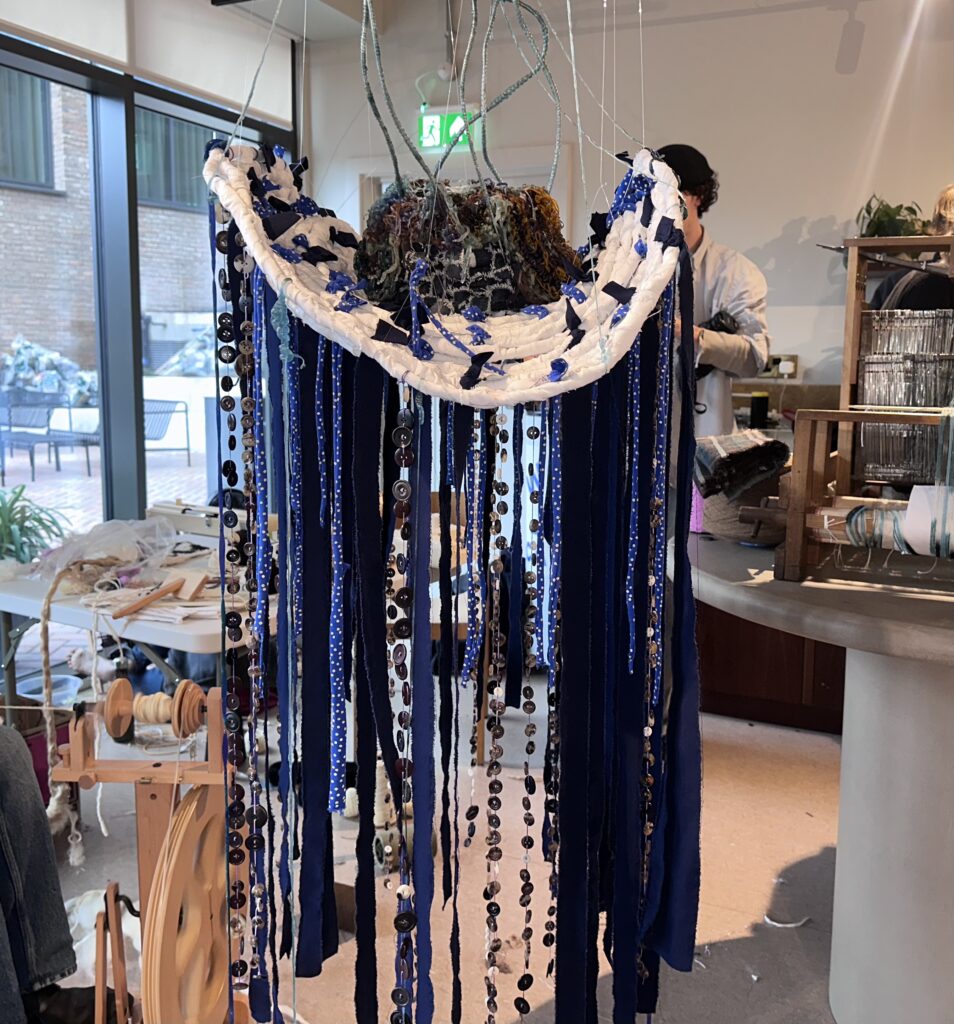 Inside Central Saint Martins’ Makers Camp: West African Makers in Focus 5 A vertical textile installation titled 'Nka Mbom' featuring draped blue and white patterned jacquard fabrics, created by Travis Obeng-Casper during the Makers Camp.