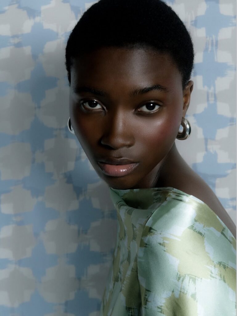 Joanna Masiyiwa Has Only Photographs. Amayi Is the Rest. 25 Amayi Archive One: model in hand-painted abstract print top against blue brushstroke backdrop, Joanna Masiyiwa debut collection