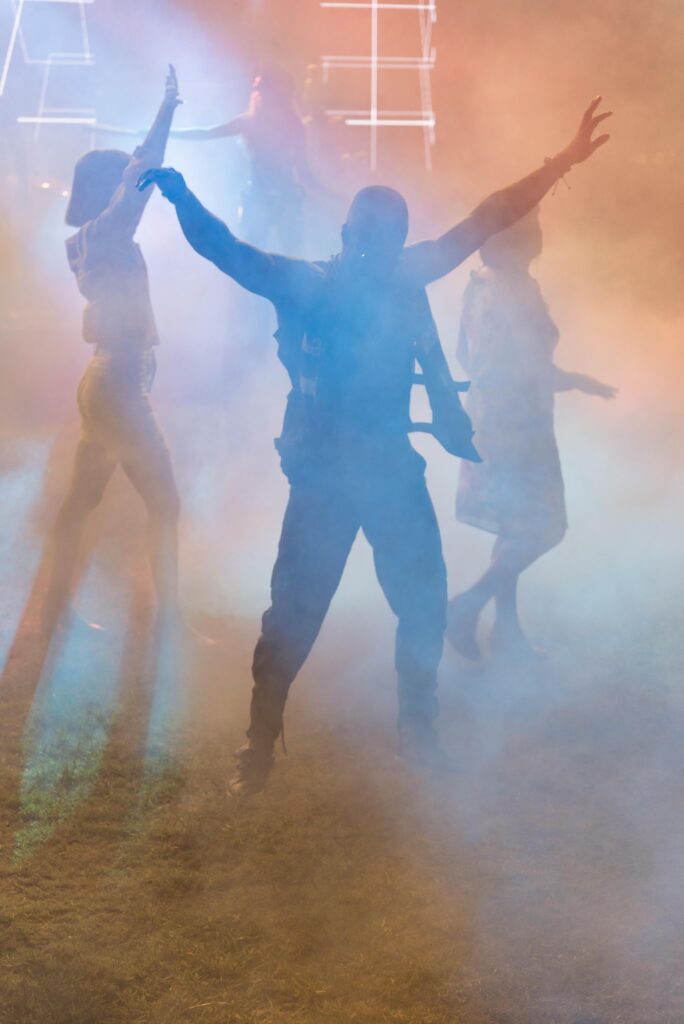 Dancers in colorful smoke at night at a rave party.