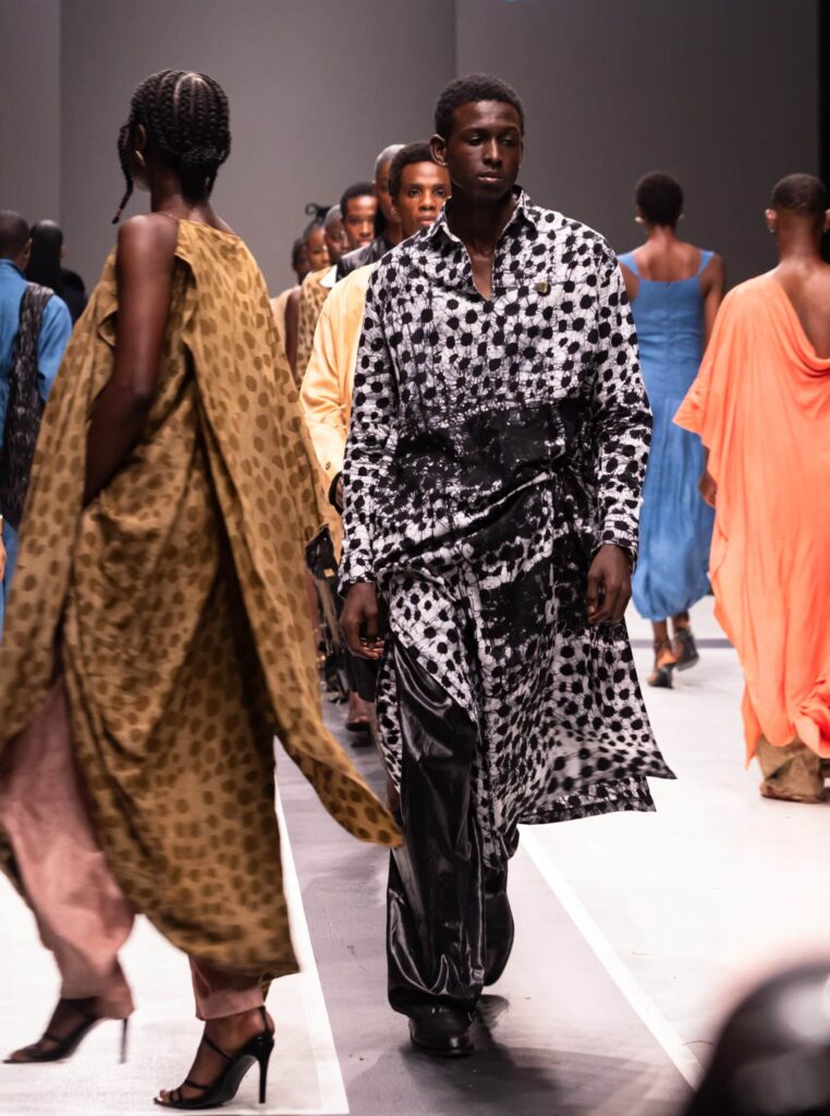 Models on a runway showcasing Olooh’s signature patterned garments, blending traditional West African influences with contemporary tailoring.