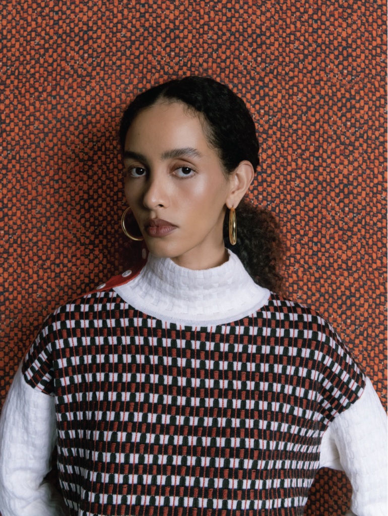 Amayi Archive One: two models in checkered knit jackets, red and white geometric pattern with blue abstract sweater, Archive One knitwear