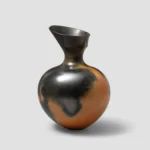 A hand-built, burnished terracotta vessel by Magdalene Odundo (1985) featuring a smooth, rounded body and a flared neck, showcasing the artist's signature orange and carbon-black polished finish.