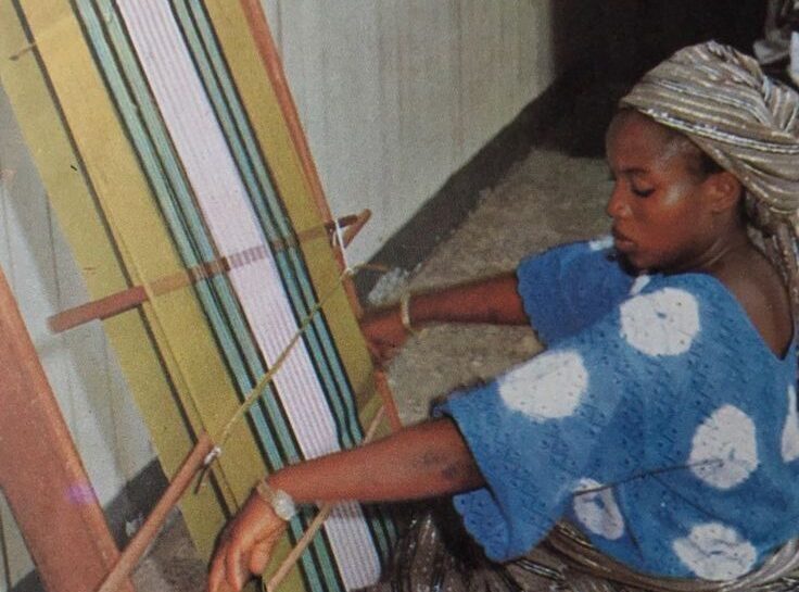 A Yoruba woman weaves Aso-Oke cloth on an upright narrow-band loom in a workshop in Iseyin, Nigeria, the historic center of Aso-Oke production.