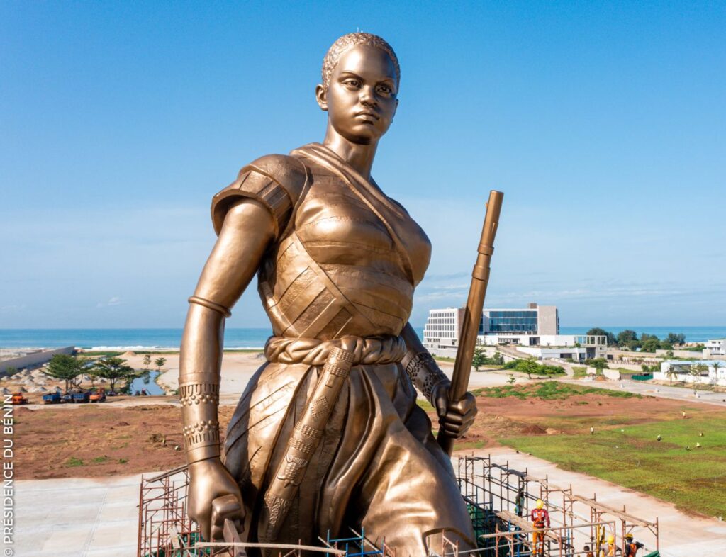 Cotonou Knows Exactly What It's Doing 4 Bronze Amazone statue seen from behind overlooking construction and city infrastructure in Cotonou, Benin.