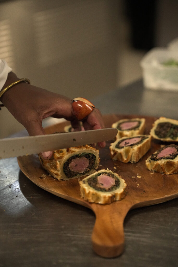 Kondokpo: Georgiana Viou and Nokx Majozi at Sofitel Cotonou 4 A chef slicing into a Wellington lamb dish, prepared with jus des carcasses and Uda pepper, during the Kondokpo culinary event.