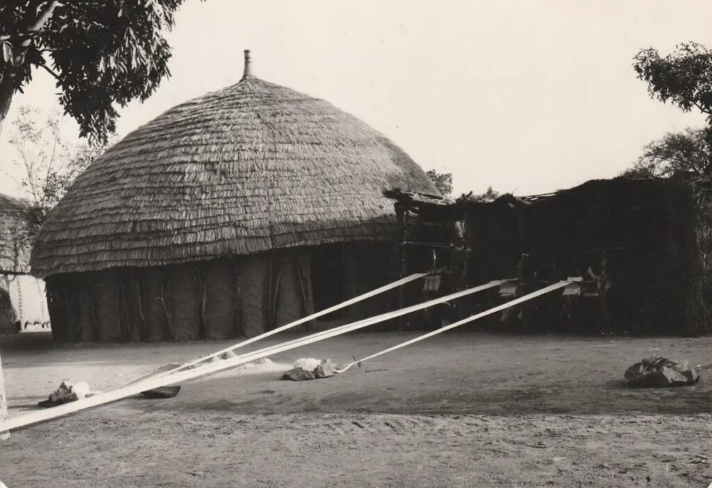 Black and white 1960 photograph documenting a traditional Fulani weaver operating a narrow-strip loom in Moyenne-Guinée.