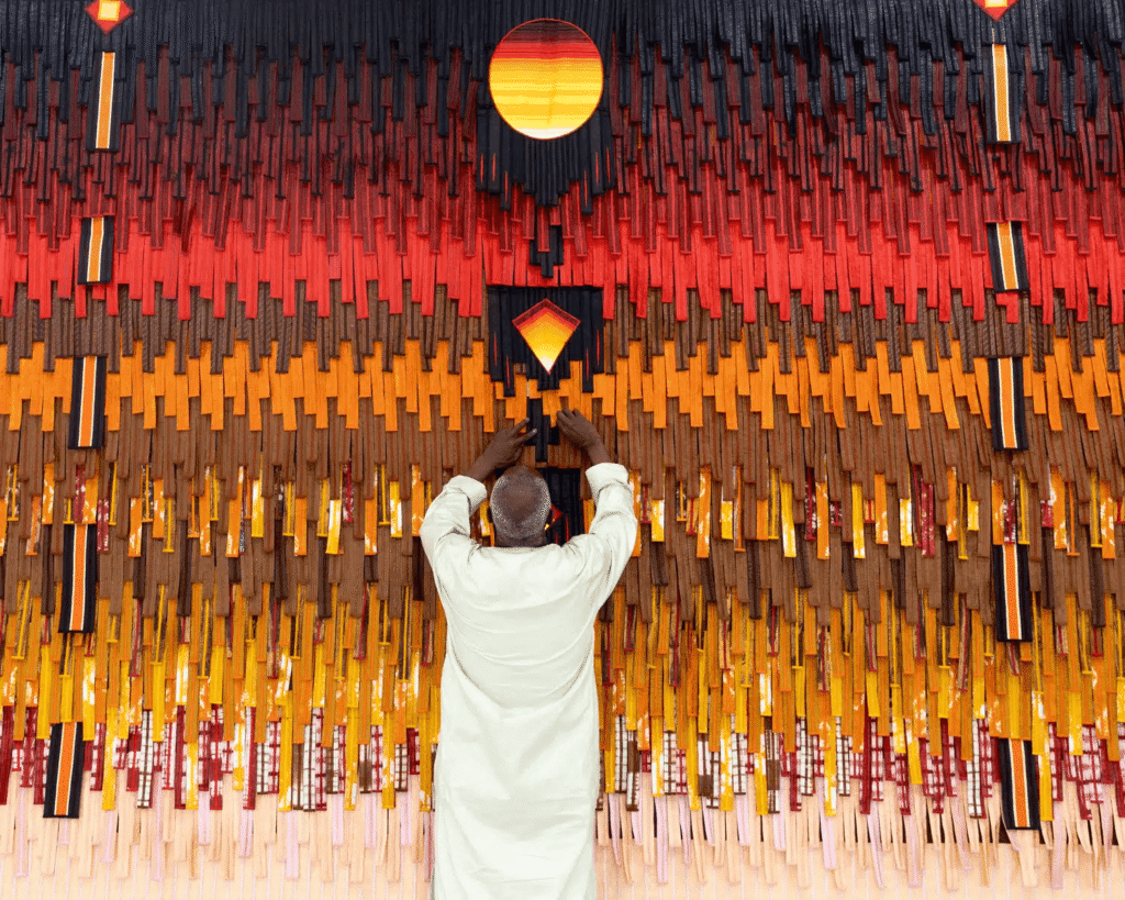 Woven Stories: 9 African Artists Shaping Contemporary Narratives Through Textiles 5 Monumental fabric installation titled 'Source de lumière (Soleil) Motif d'Arabie sur Fond Ocre' by Malian artist Abdoulaye Konaté, showcasing contemporary African textile art.
