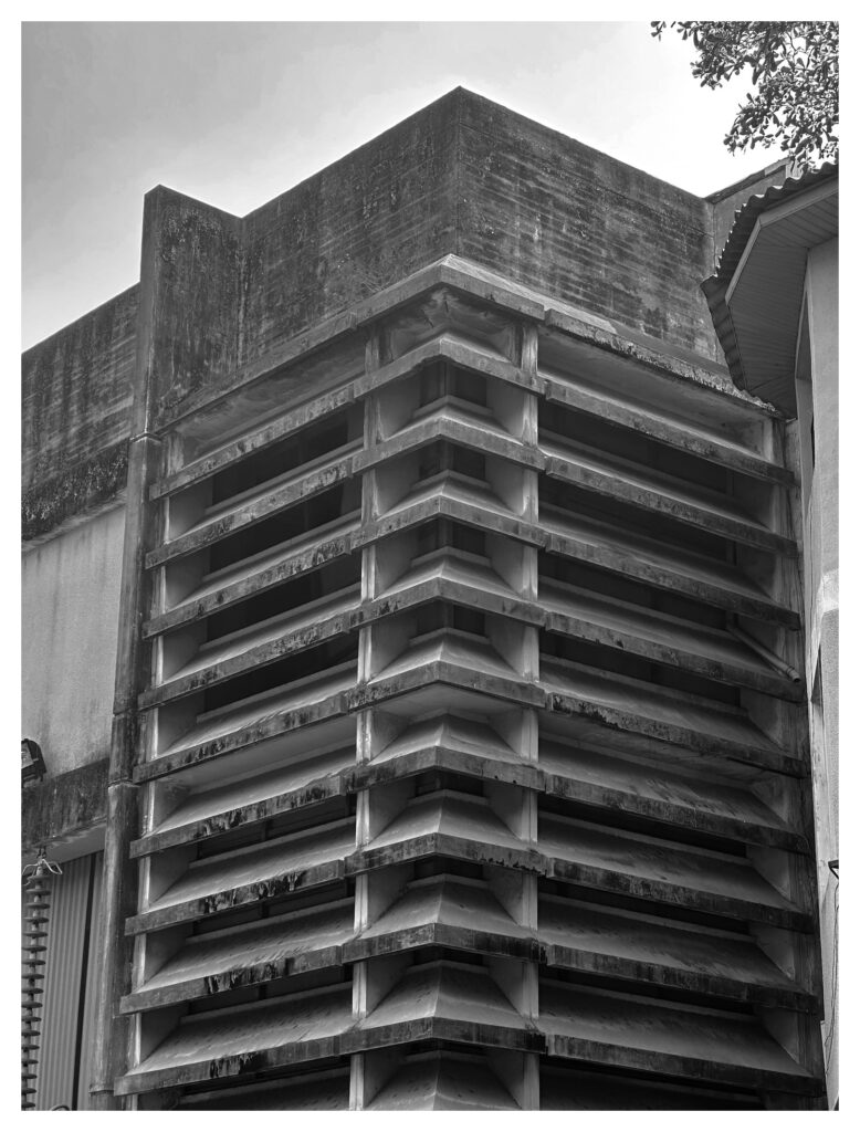 Close-up of stacked horizontal concrete louvers forming a chevron pattern at the corner of a weathered brutalist building at the University of Lagos.