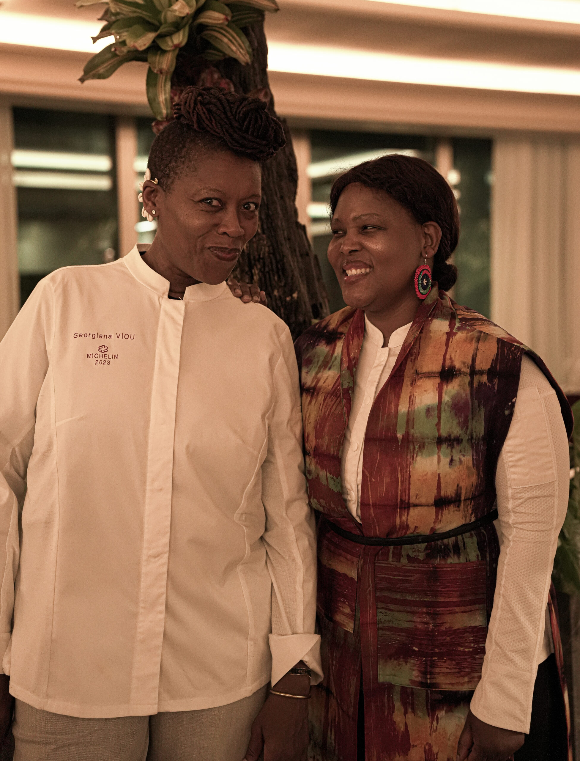 Chef Georgiana Viou and Chef Nokx Majozi standing side-by-side in custom chef coats during the Kondokpo culinary event at Sofitel Cotonou.