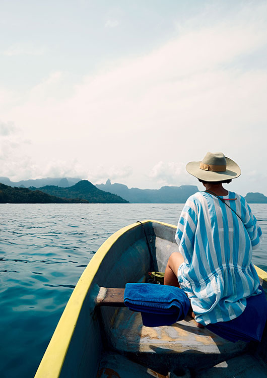 IMAGE 4: SMALL-principe52-1.jpg] Alt: Guest on a traditional boat trip off Príncipe Island with volcanic peaks in the distance Meta description: Boat trip off Príncipe Island. Volcanic peaks through low cloud.