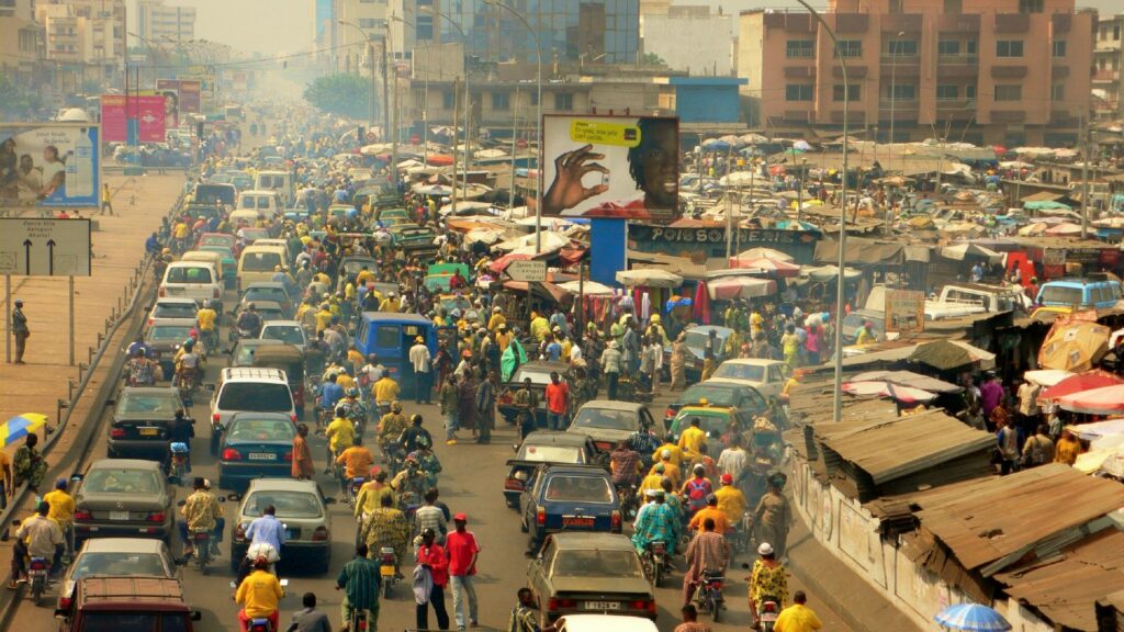 Cotonou Knows Exactly What It's Doing 3 Dense traffic and market activity on a main road near Dantokpa Market in Cotonou, Benin.