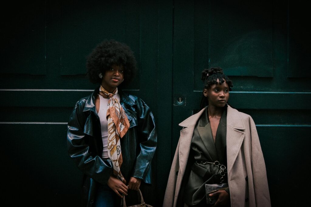 Two women in street style standing against a dark green door in an urban setting
