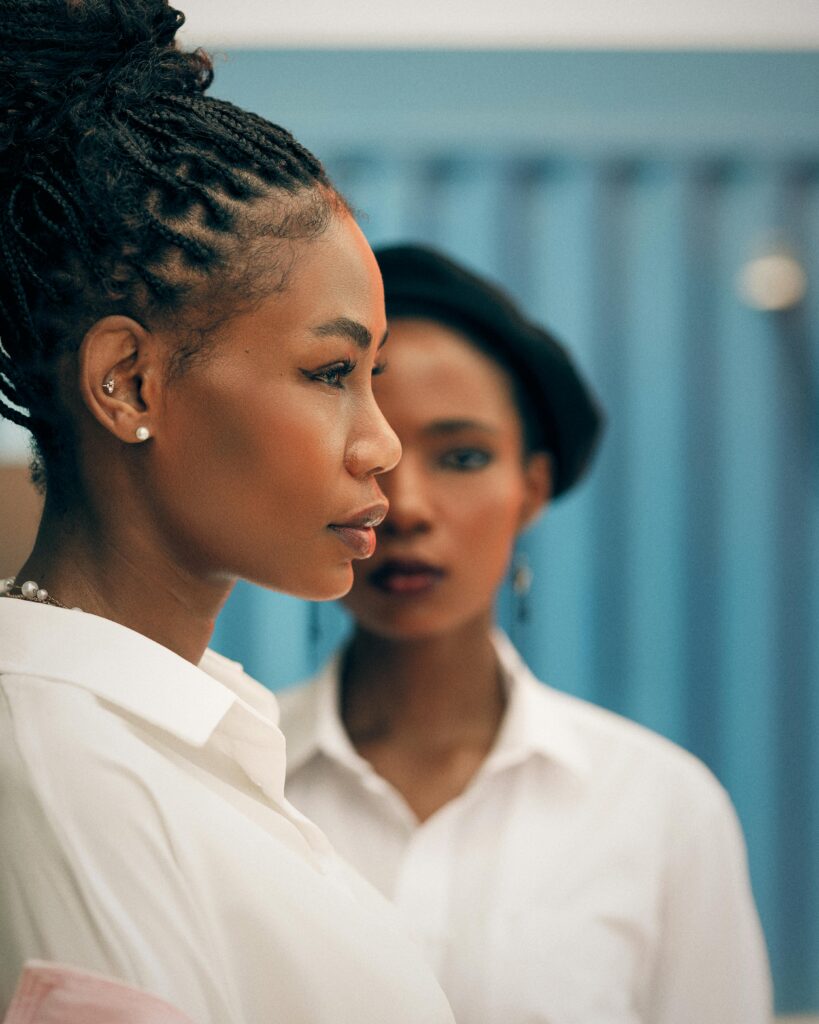 Two young women in white shirts photographed in profile against a blue background