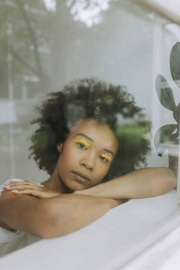 Woman resting her chin on her arms on a windowsill, gazing through the glass