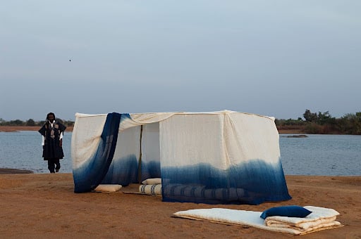 Woven Stories: 9 African Artists Shaping Contemporary Narratives Through Textiles 3 Aboubakar Fofana's indigo-dyed textile installation, 'Tente moustiquaire,' set on the sandy banks of the Niger River in Mali.
