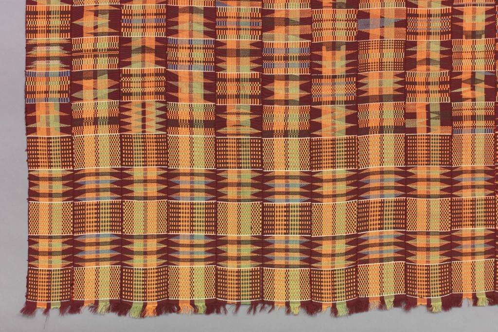 Kente and the Politics of Being Read 4 Densely patterned Asante adwenasa kente in orange, maroon, and green, every block woven with a different motif.