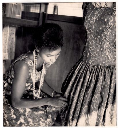 Designer Shade Thomas-Fahm fitting a garment on a dress form in a black-and-white archival photo