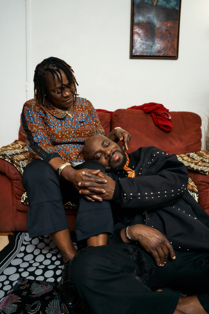 A couple photographed against bold patterned cloth in Generational Love, their bodies turned toward one another