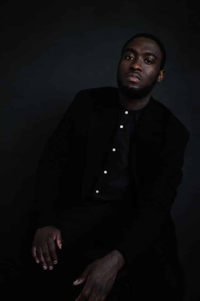 A pensive young African man stands in soft light, reflecting the questions a new generation is asking about marriage and adulthood.