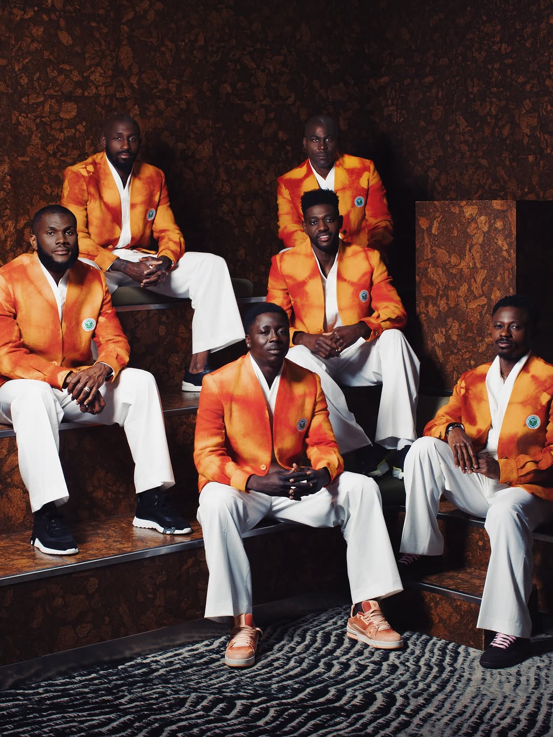 Ibrahim Fernandez ceremonial look for Cote d'Ivoire: men in structured saffron-orange jackets and white trousers, the Elephants' off-pitch World Cup wardrobe.