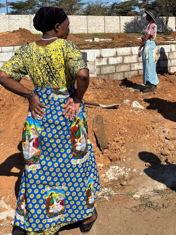 A woman wearing a Holy Family chitenge wrapper at a building site in Zambia