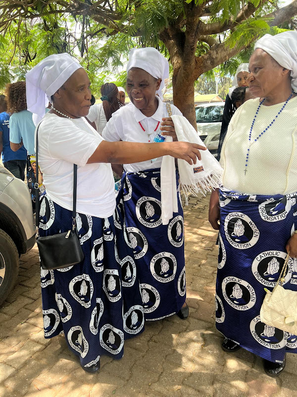 Members of the Catholic Women Organisation in matching praying-hands insignia chitenge wrappers outside Mass at Chelstone Catholic Church, Lusaka