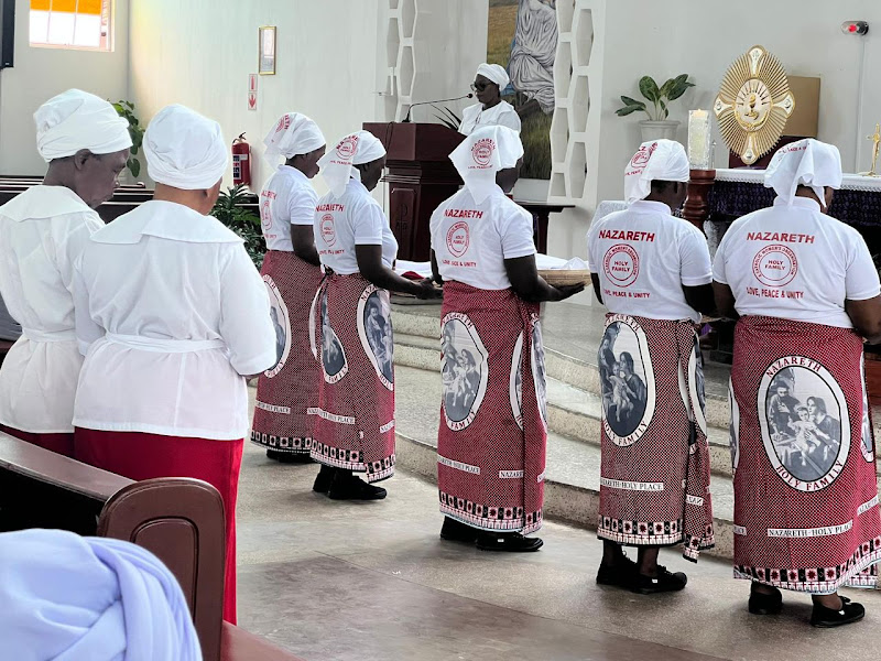 Members of the Nazareth Holy Family group, a Catholic women's organisation in white head coverings and printed chitenge wrappers, carrying offerings toward the altar during Mass at Chelstone Catholic Church, Lusaka