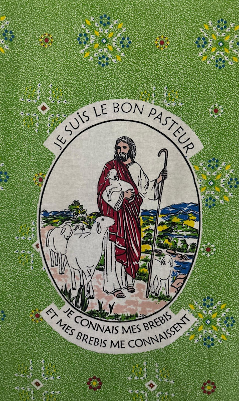 Devotional chitenge with a Good Shepherd print lettered 'Je suis le bon pasteur' on a green ground, sold in Zambian markets