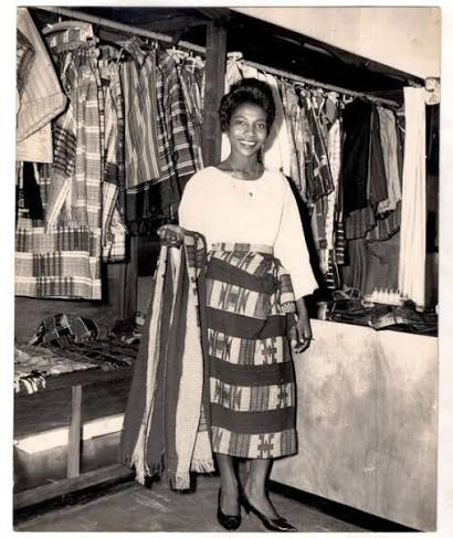 Shade Thomas-Fahm holding lengths of striped aṣọ-òkè cloth in her studio