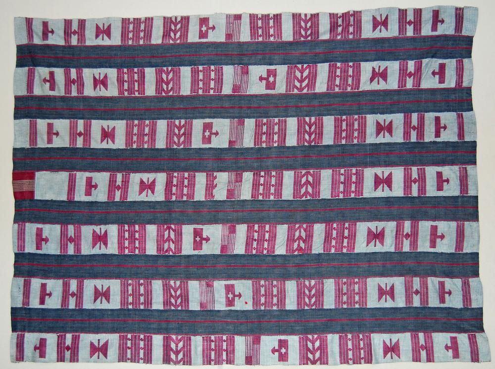 A ceremonial aṣọ-òkè cloth woven in bold magenta and indigo geometric strips