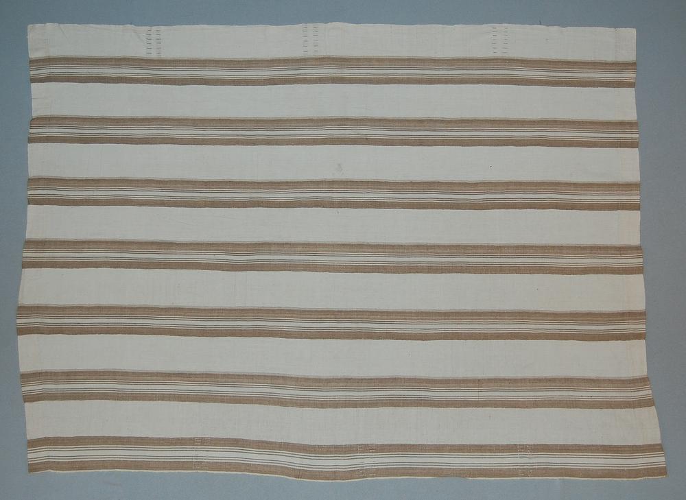 A handwoven aṣọ-òkè cloth with fine cream and brown warp stripes laid flat