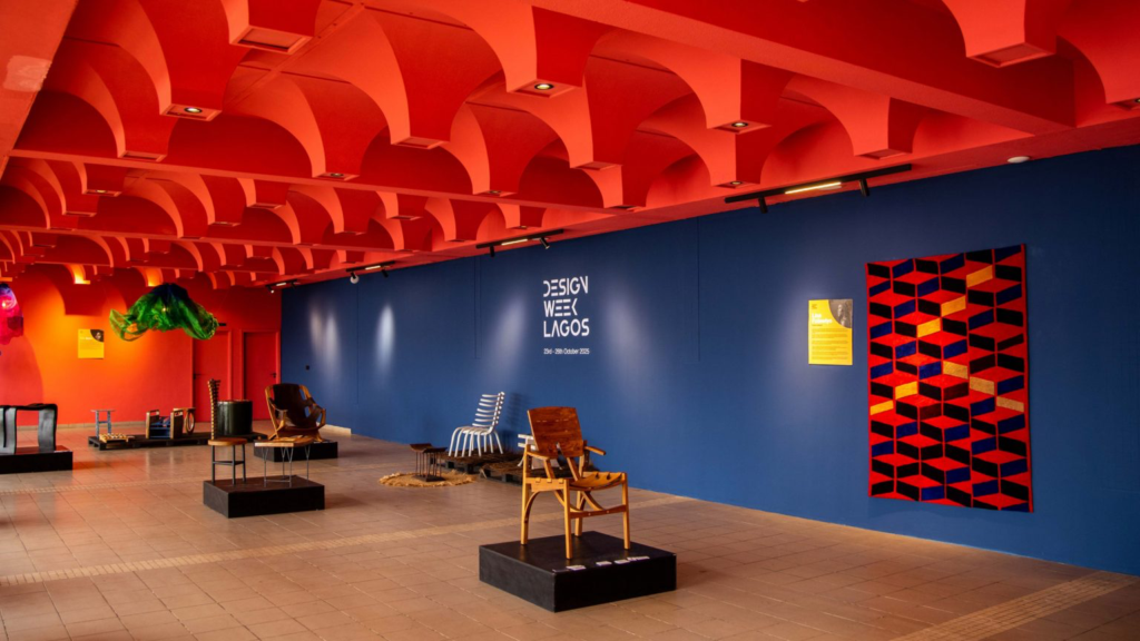 Design Week Lagos 2025, chairs on black plinths beneath a red vaulted ceiling beside a navy wall and geometric textile