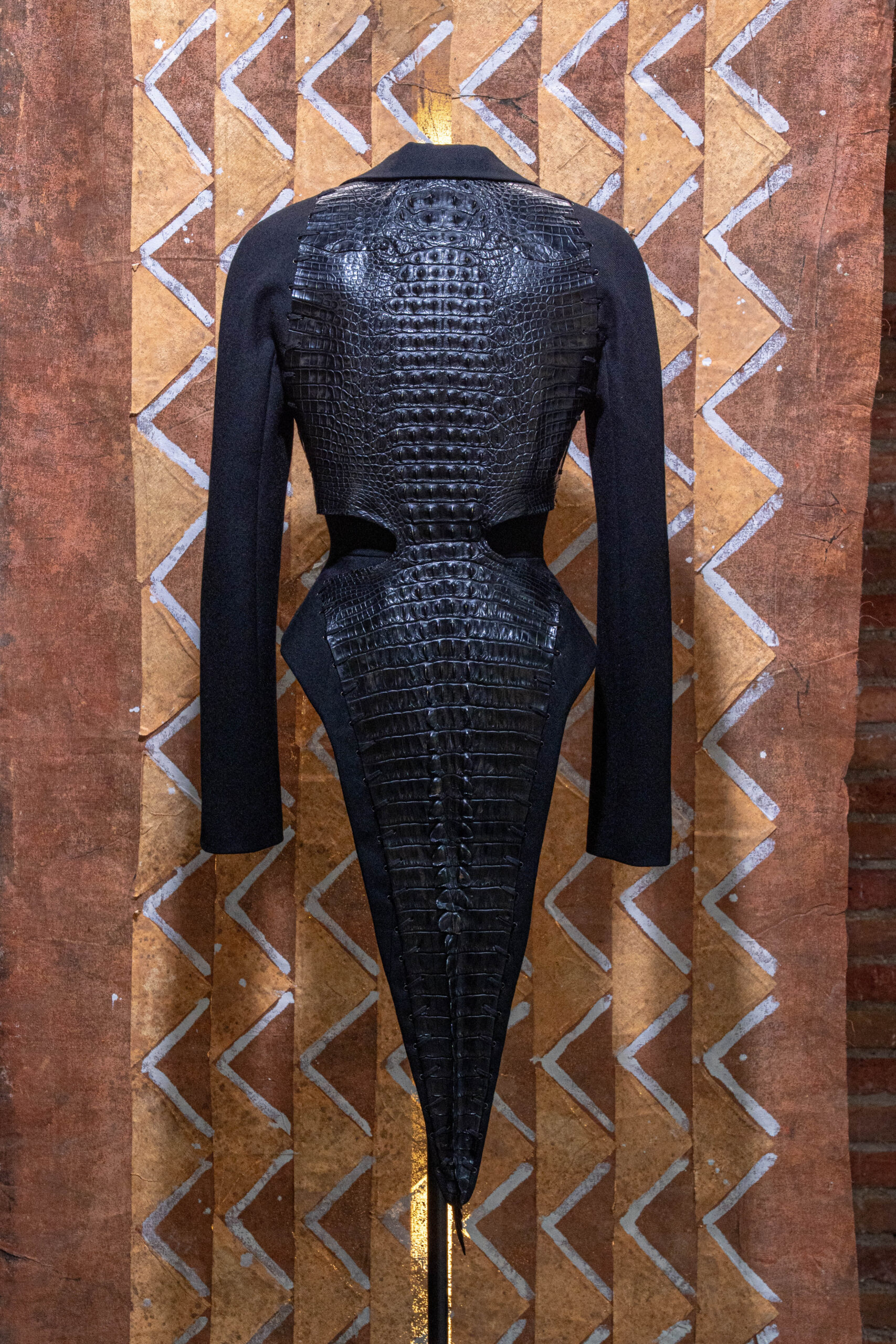 Azzedine Alaïa crocodile-spine jacket displayed against African mudcloth chevron patterns