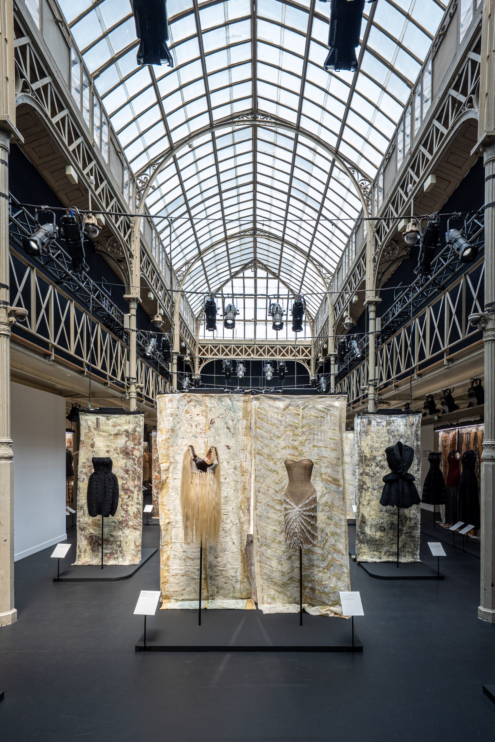 Wide view of the iron-and-glass hall of the Fondation Azzedine Alaïa with garments under the vaulted roof