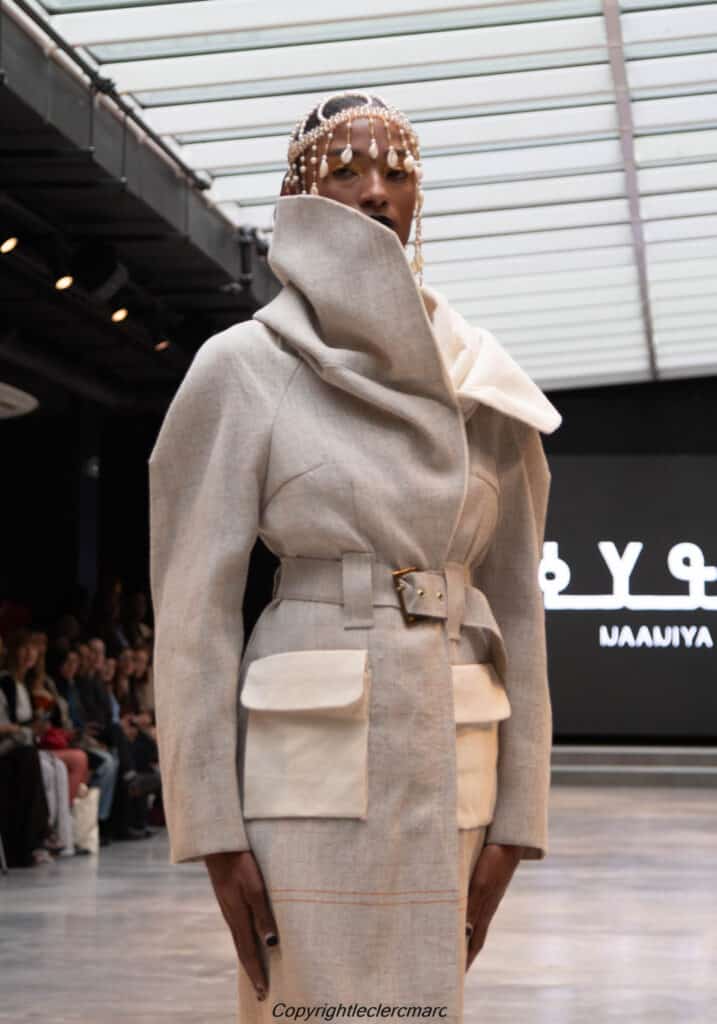 Model in a grey belted wrap coat with oversized collar, NAANIYA SS26 Tombouctou collection at Paris Fashion Week