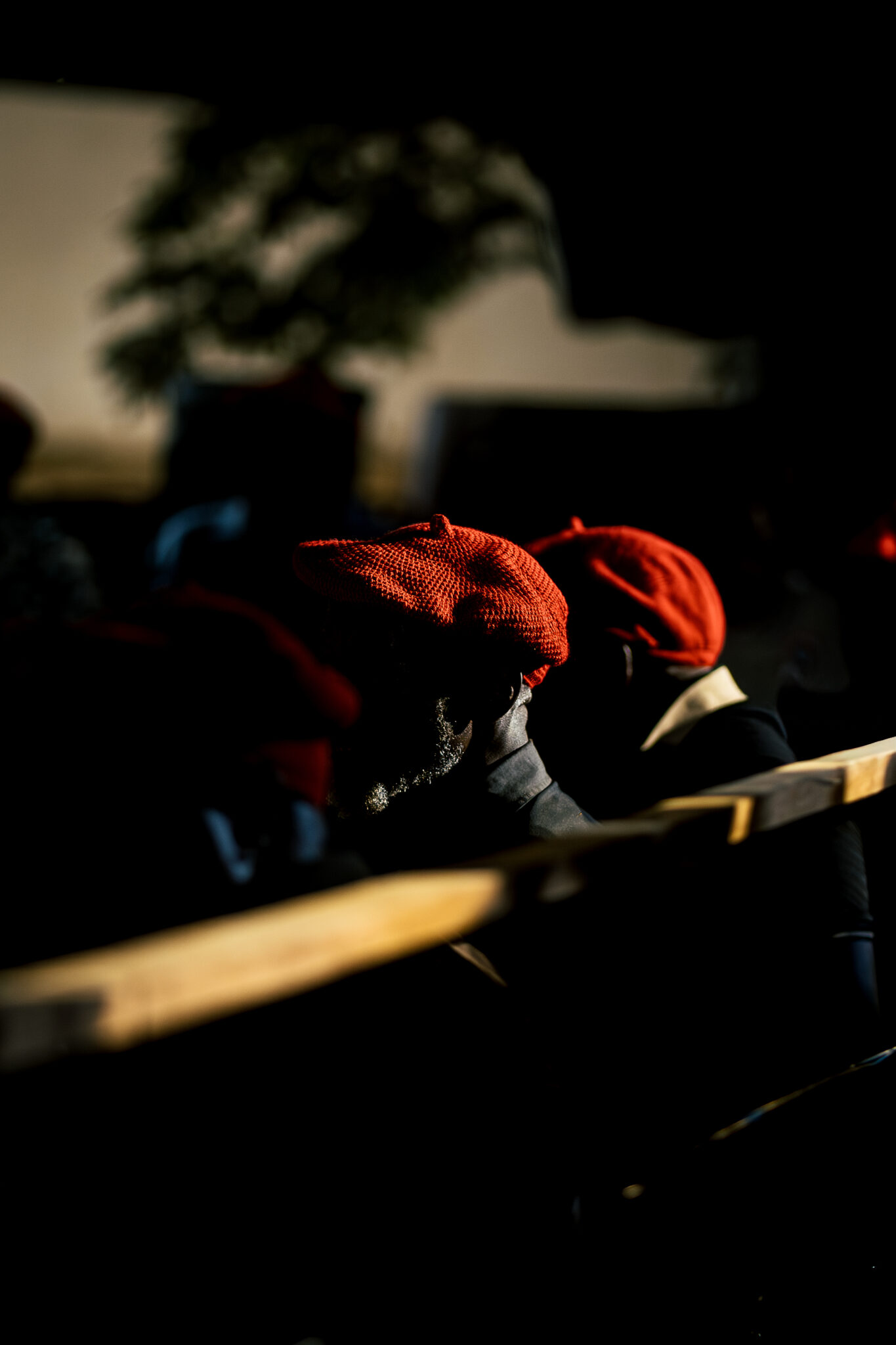 Six Days on the Zambezi: A Traveller's Guide to Kuomboka 8 Malozi men in traditional red Lishushu berets in low light behind a paddle at the Kuomboka ceremony in Western Zambia.