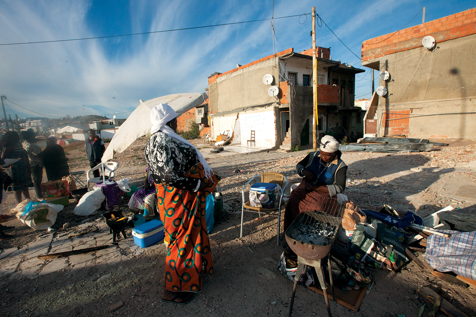 Two women prepare food on an open grill amid the rubble of demolished homes in Bairro 6 de Maio, a Cape Verdean neighbourhood outside Lisbon.